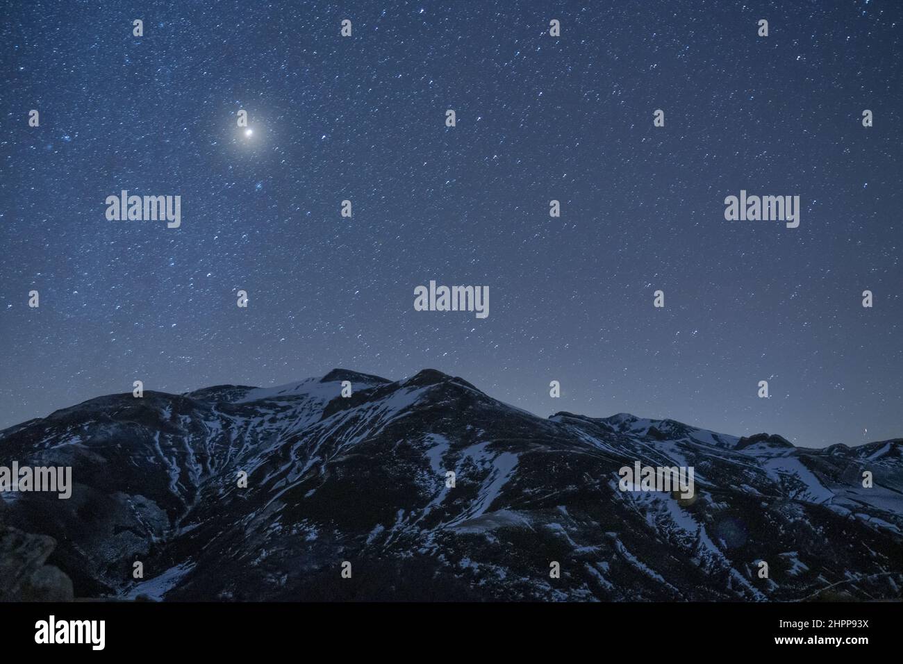 Scenic view of a slope of a snowy mountain under the starry night sky
