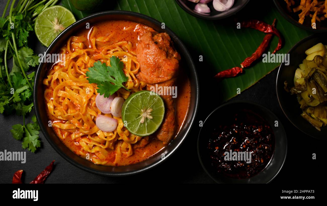Flavourful Khao Soi Kai, creamy and slightly spicy yellow curry with chicken drumstick. top view, Northern Thai cuisine concept. Stock Photo