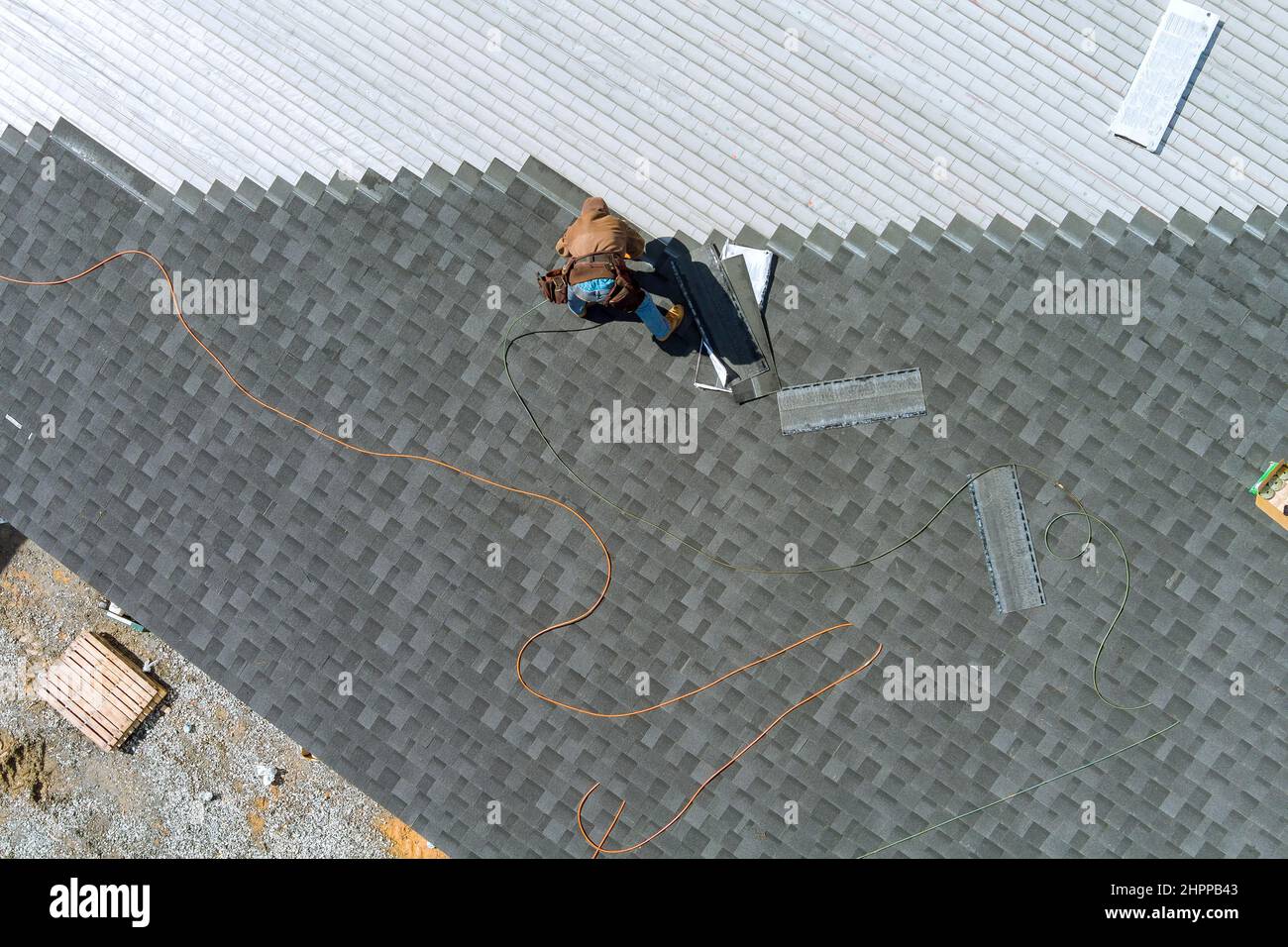 A asphalt shingles installation on the roof roofer is nailing asphalt