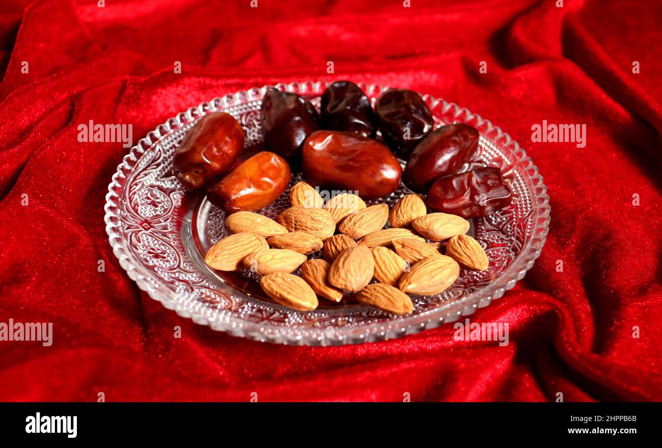 Almond and date on a glass plate with red velvet background,Healthy dry food Stock Photo