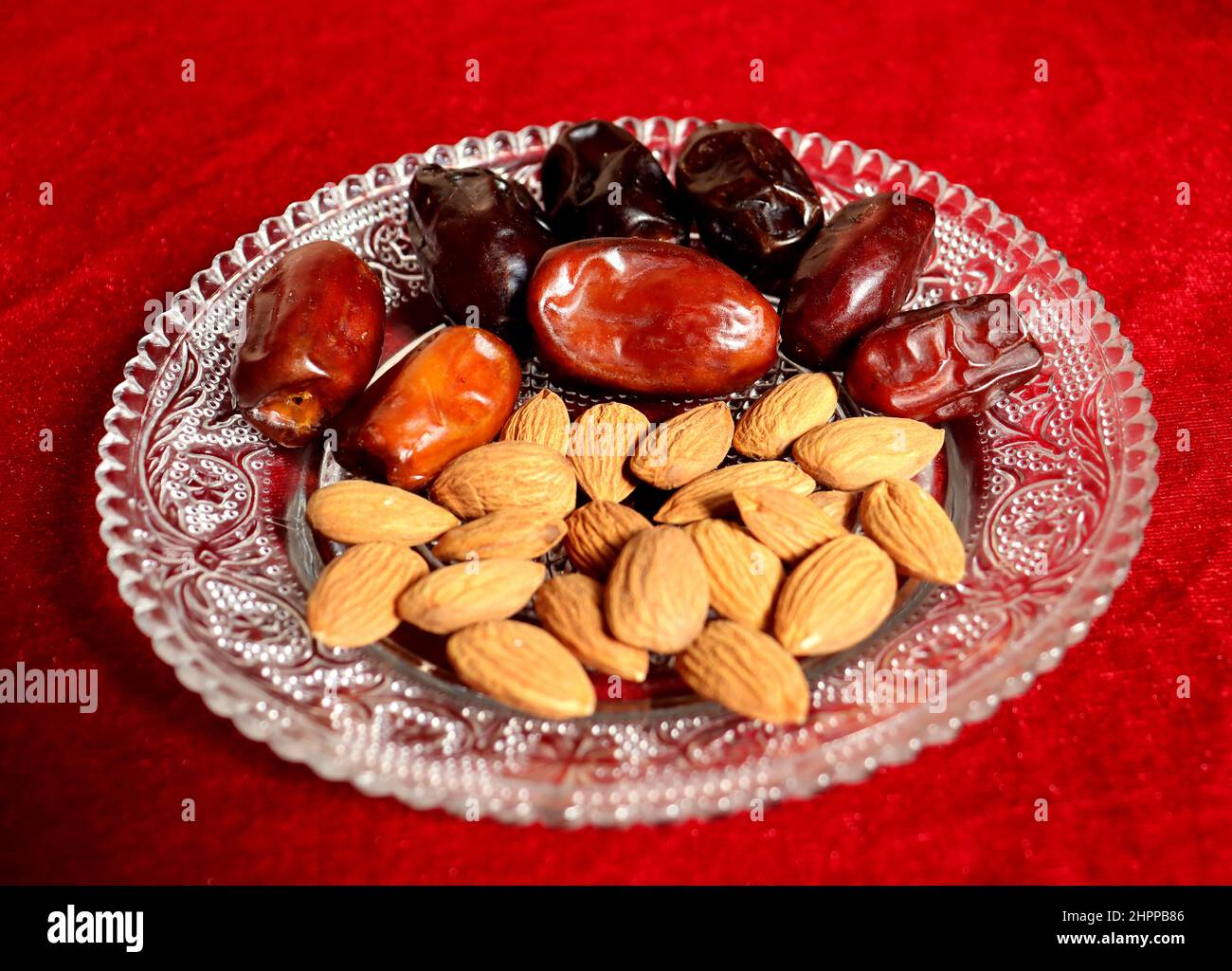 Healthy Dry food for breakfast,Almond and Arabic date on a glass plate with white background,healthy foodwith antioxident Stock Photo