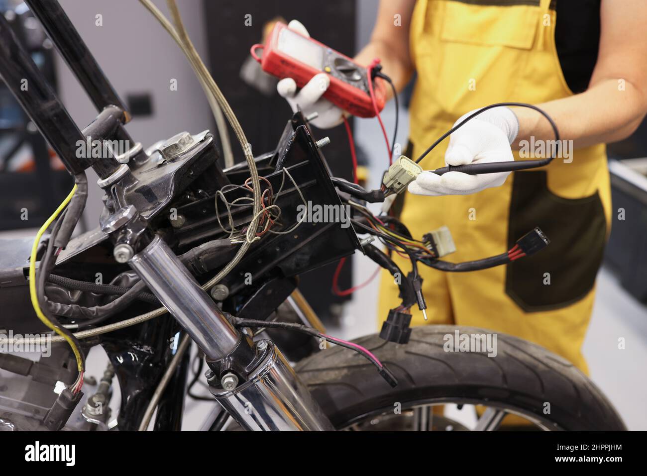 Mechanic using multimeter checks voltage level motorcycle battery motorcycle garage Stock Photo