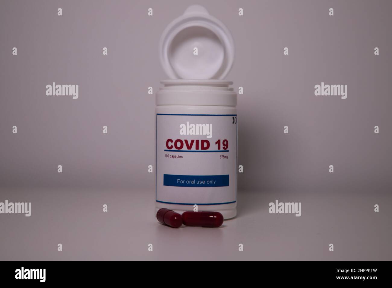 Covid19 pill bottle with several pills outside the bottle and a US flag on a lab bench Stock Photo