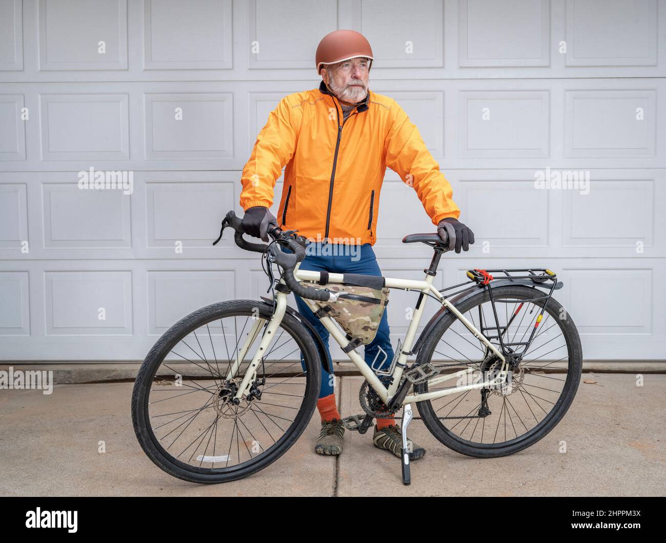 senior make cyclist standing with his touring bike in a driveway Stock Photo