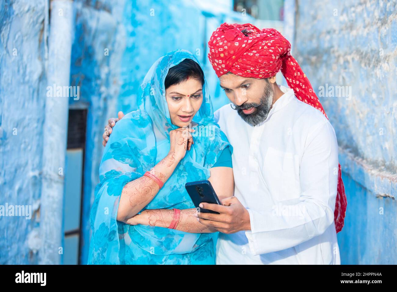 Surprised traditional indian couple using smart phone watching video.  Smiling man wearing red turban and woman in sari with mobile phone.  Rajasthani p Stock Photo - Alamy