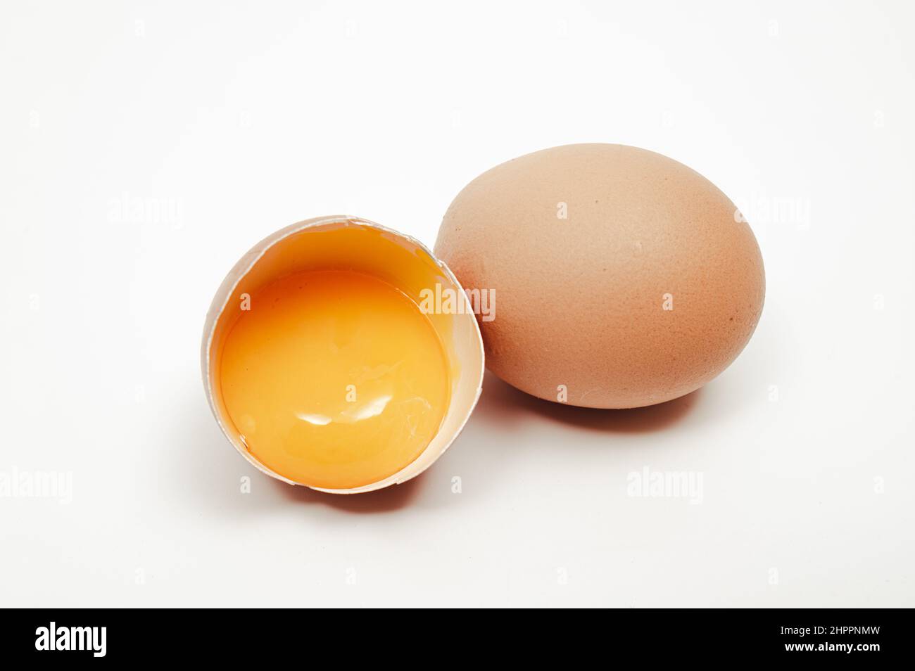 Broken egg with yolk visible on white background Stock Photo