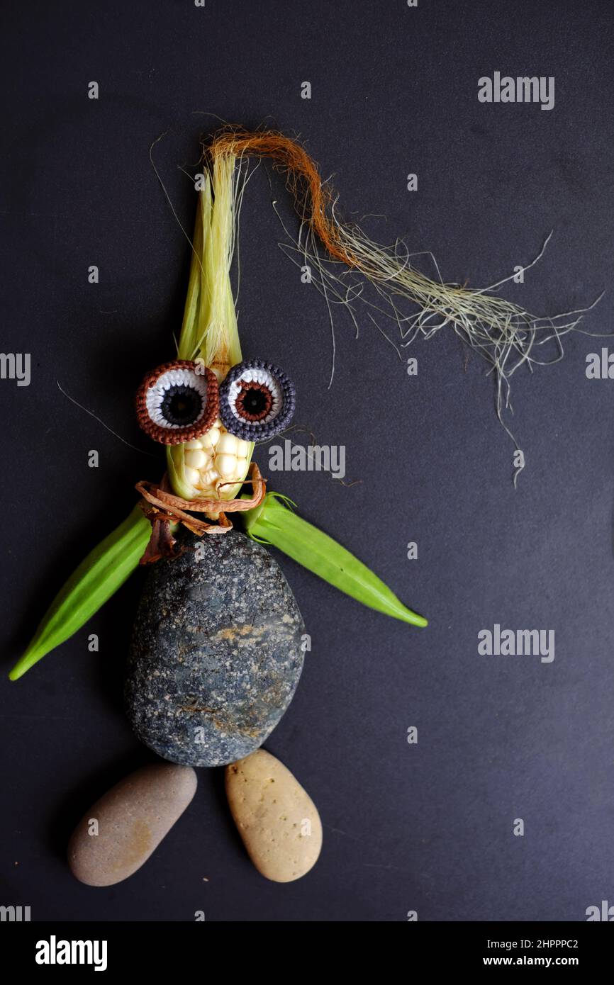 Funny face set up from food, agriculture product from rooftop garden, small corn, pumpkin flower, corn silk, okra fruit, pebble and eyes crochet from Stock Photo