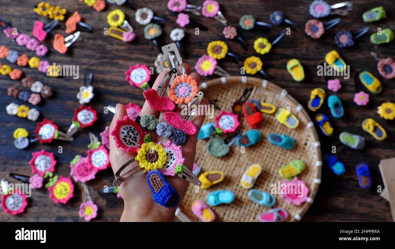 Top view Vietnamese woman hand hold handmade product, crochet hair pin in many shape and colorful, pretty handcraft gift accessories for beauty on bla Stock Photo
