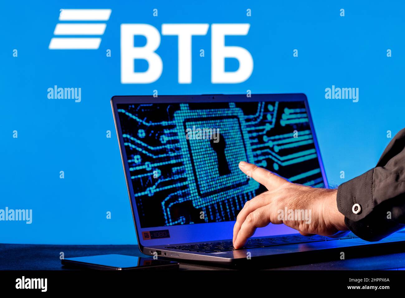 Laptop with lock symbol on screen on background of  VTB bank logo. Finger points to lock symbol. Concept of data hacking. Stock Photo