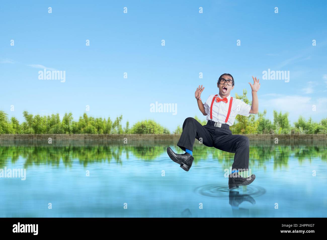 Asian nerd with ugly face falling on the lake Stock Photo