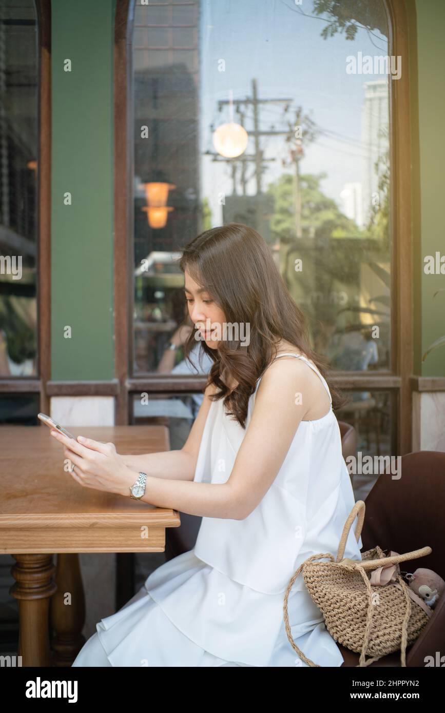 Business asian women use smartphone sitting in coffee shop day light ...