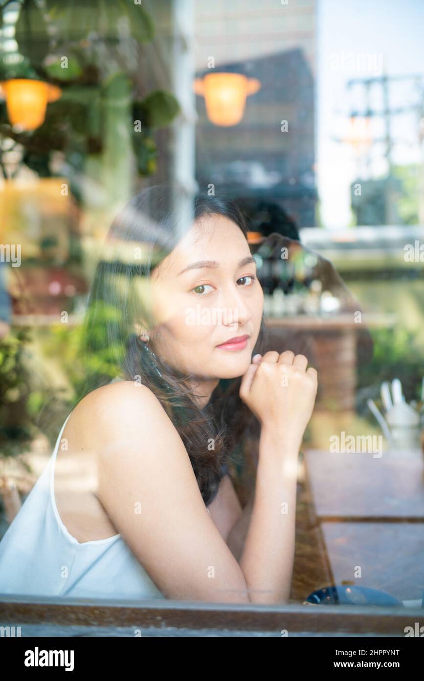 Beautiful asian women sitting in urban coffee shop looking out of ...