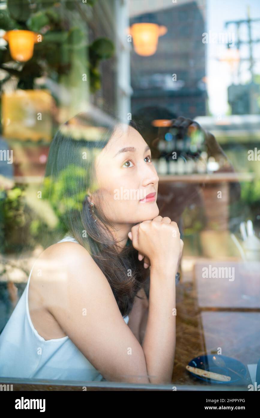 Beautiful asian women sitting in urban coffee shop looking out of ...