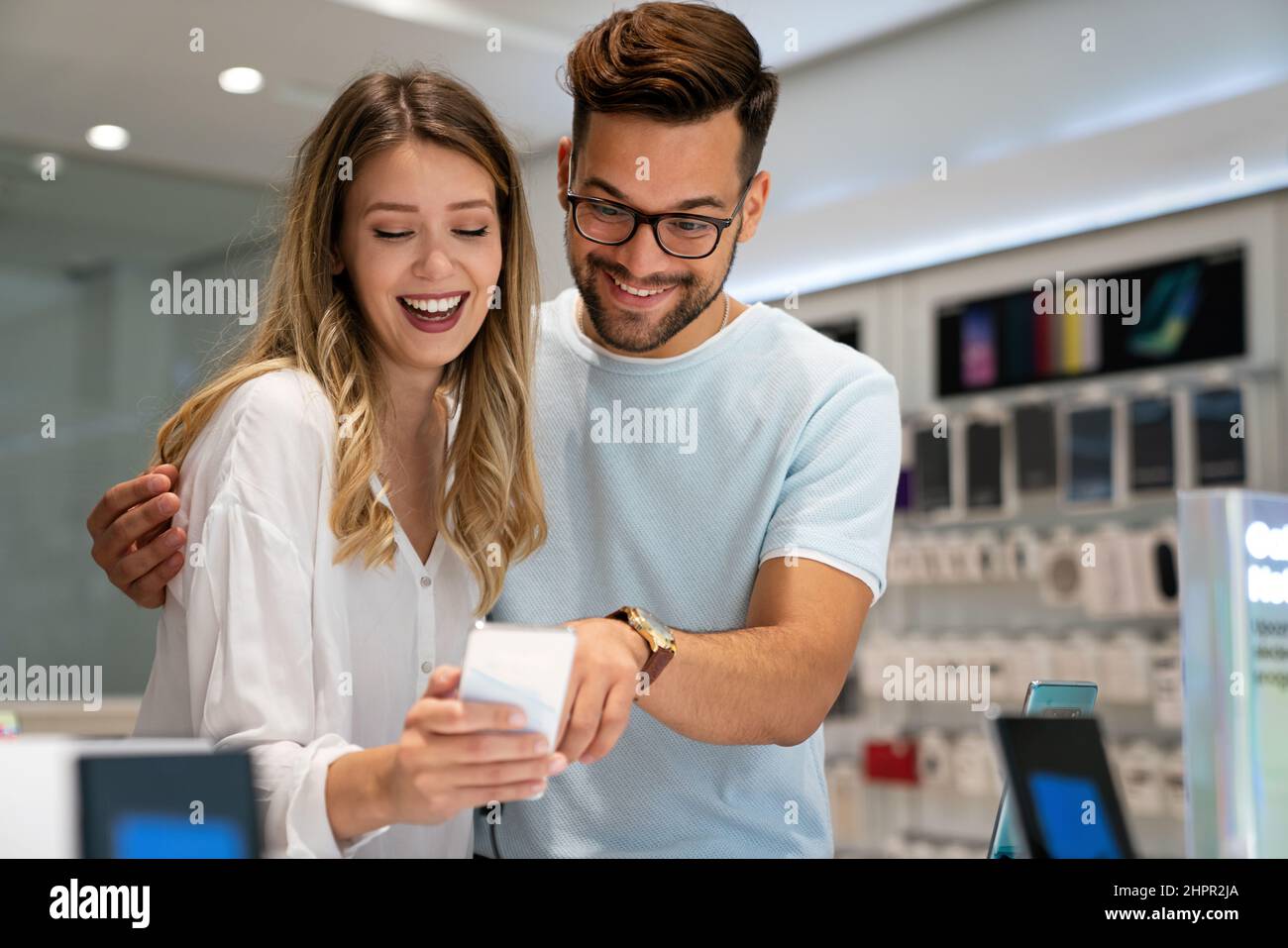 Happy young people buying new smartphone in mobile shop. Technology device shopping concept Stock Photo