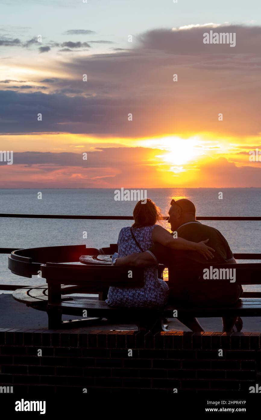 Couple watching the sun setting over the sea on the east coast of England at Hunstanton. Stock Photo