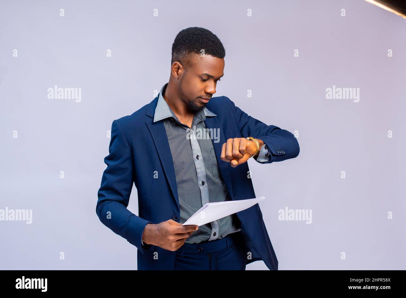 Young African man in a costume checking time on his watch Stock Photo ...