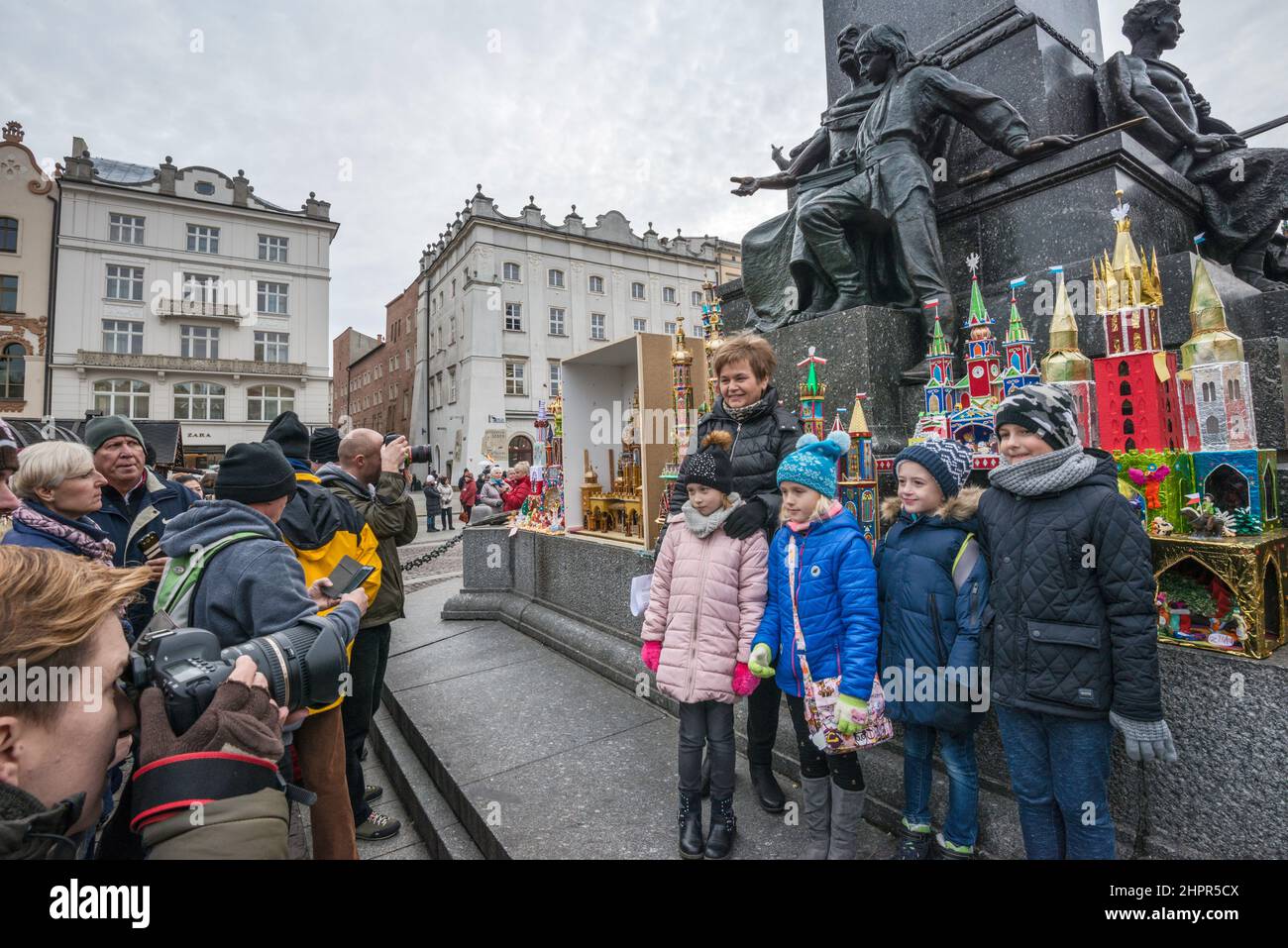 Schoolchildren posing for photos at Kraków Szopka nativity scenes displayed during annual contest in December, event included in UNESCO Cultural Heritage list, at Adam Mickiewicz monument, Main Market Square, Kraków, Poland Stock Photo