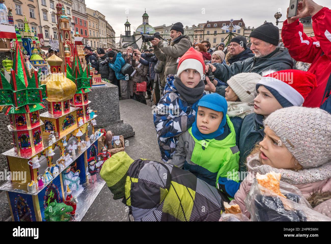 Young schoolchildren looking at Kraków Szopka nativity scenes, displayed during annual contest in December, at Adam Mickiewicz monument, Main Market Square, Kraków, Poland Stock Photo