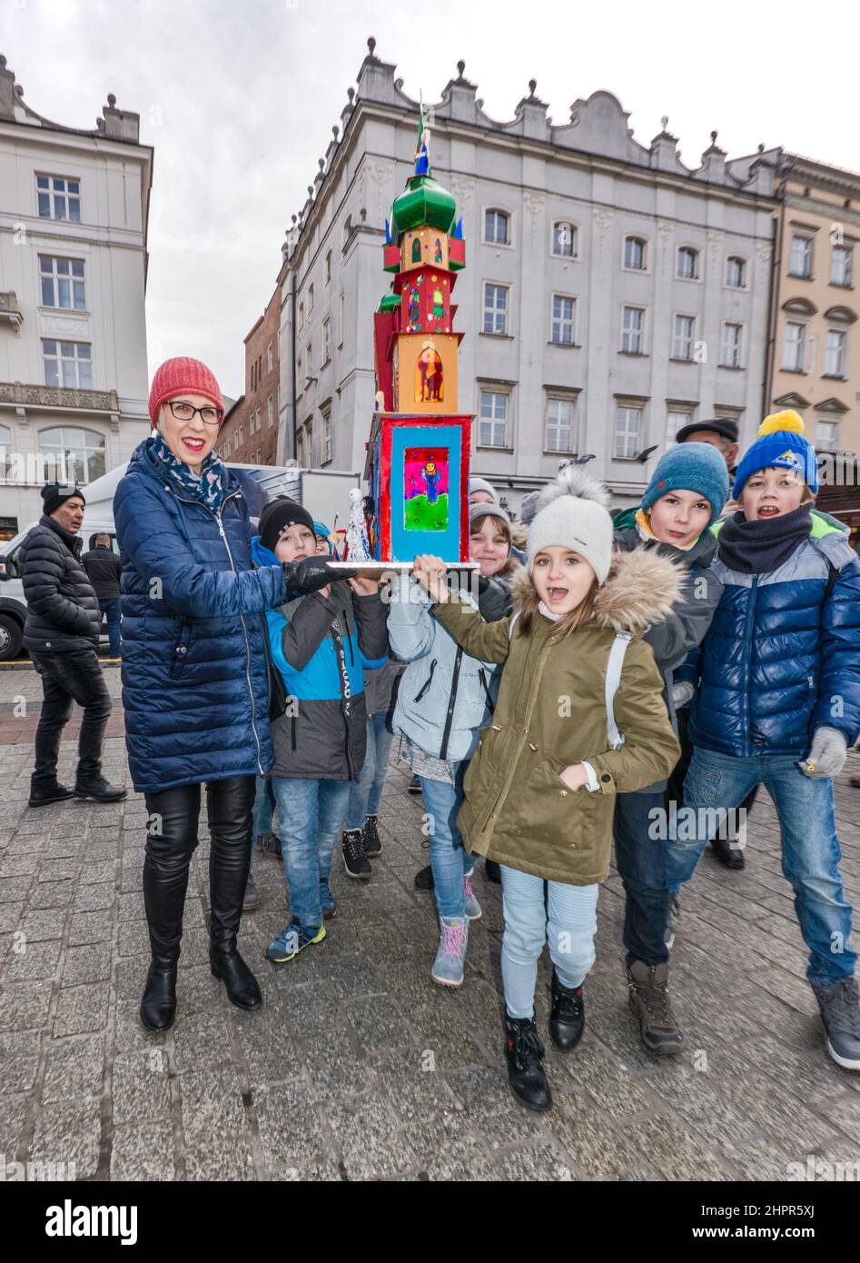 Schoolchildren, teacher, carrying Kraków Szopka nativity scene, made by them at school, for display during annual contest in December, event included in UNESCO Cultural Heritage list, at Main Market Square, Kraków, Poland Stock Photo