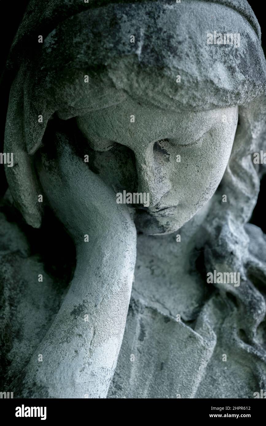 An ancient stone statue of sad and desperate woman on tomb as a symbol of death and the end of human life. Vertical image. Stock Photo