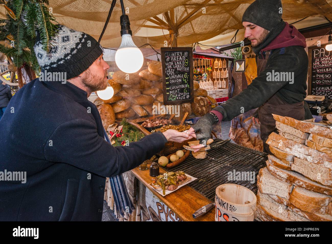 Customer, slices of bread at food stand at Christmas market, Main Market Square, Kraków, Poland Stock Photo