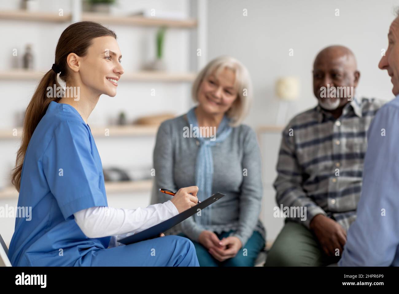 Friendly young woman doctor having conversation with senior people ...