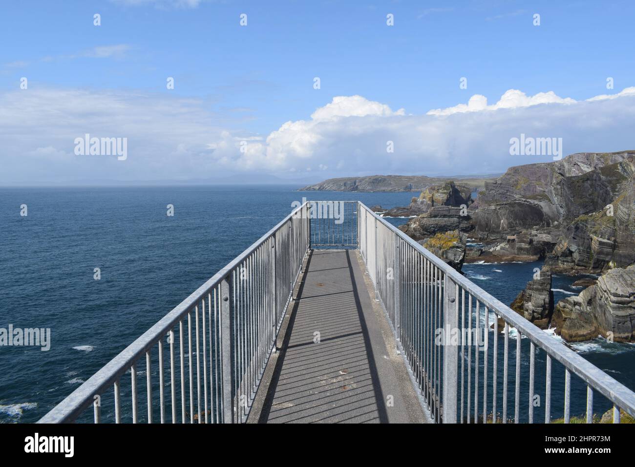 Panoramic walkaway in the sky with cliffs and sea landscape. Blue summer sky with some clouds. Mizen Head. Ireland. Stock Photo