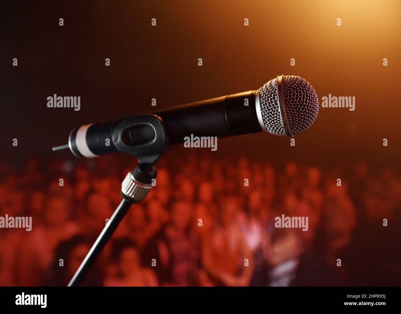 Take the stage.... A microphone standing on a stage with a crowd in the background. Stock Photo