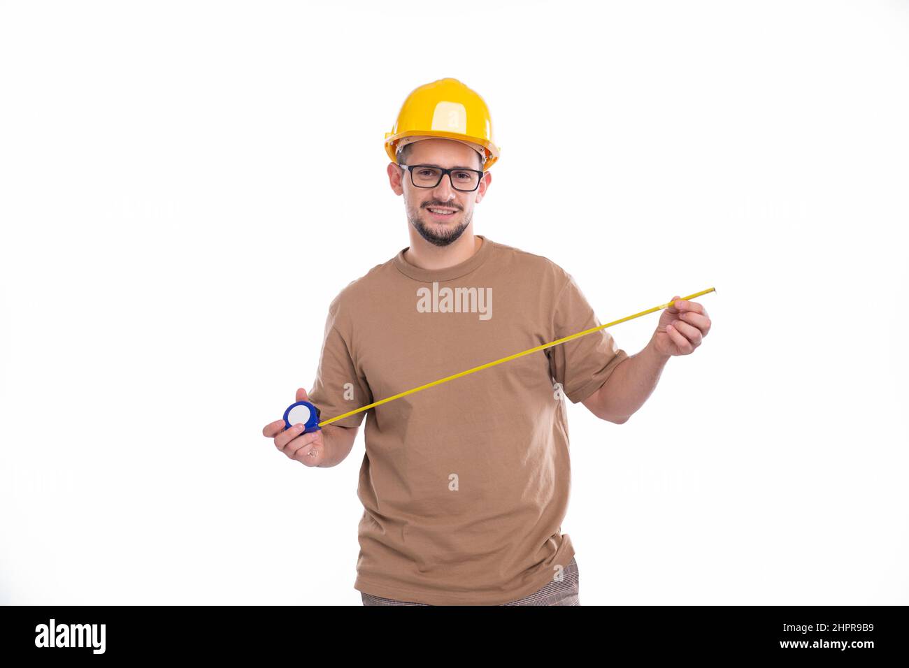 Construction Worker Checking Measuring Tape Isolated. Man Working, Looking to camera Stock Photo