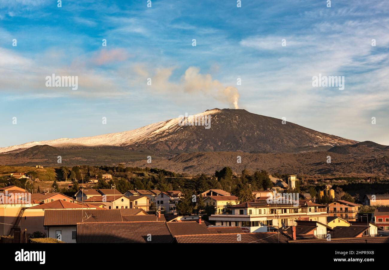 Smoke pours from Mount Etna, the most active volcano in Europe, seen at sunset from the small town of Bronte on its western flank (Sicily, Italy) Stock Photo