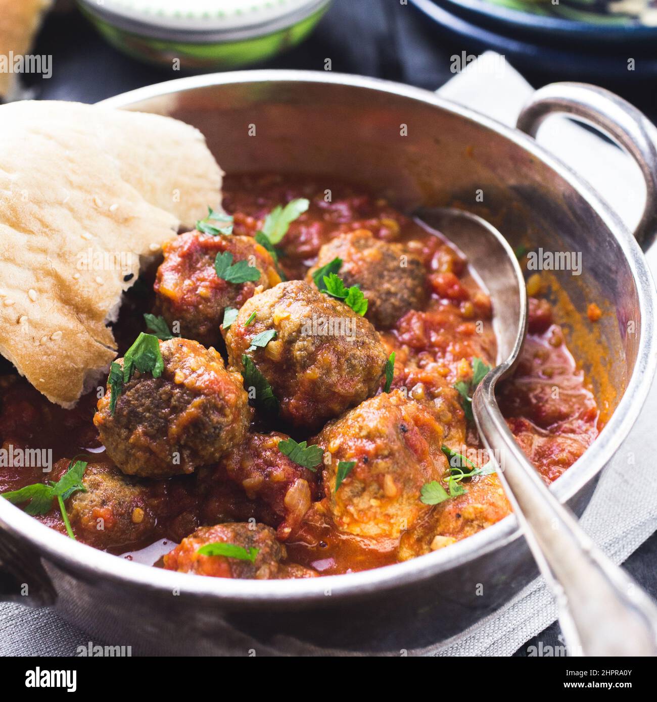 A silver bowl full of meatballs in tomato sauce in a dark rustic