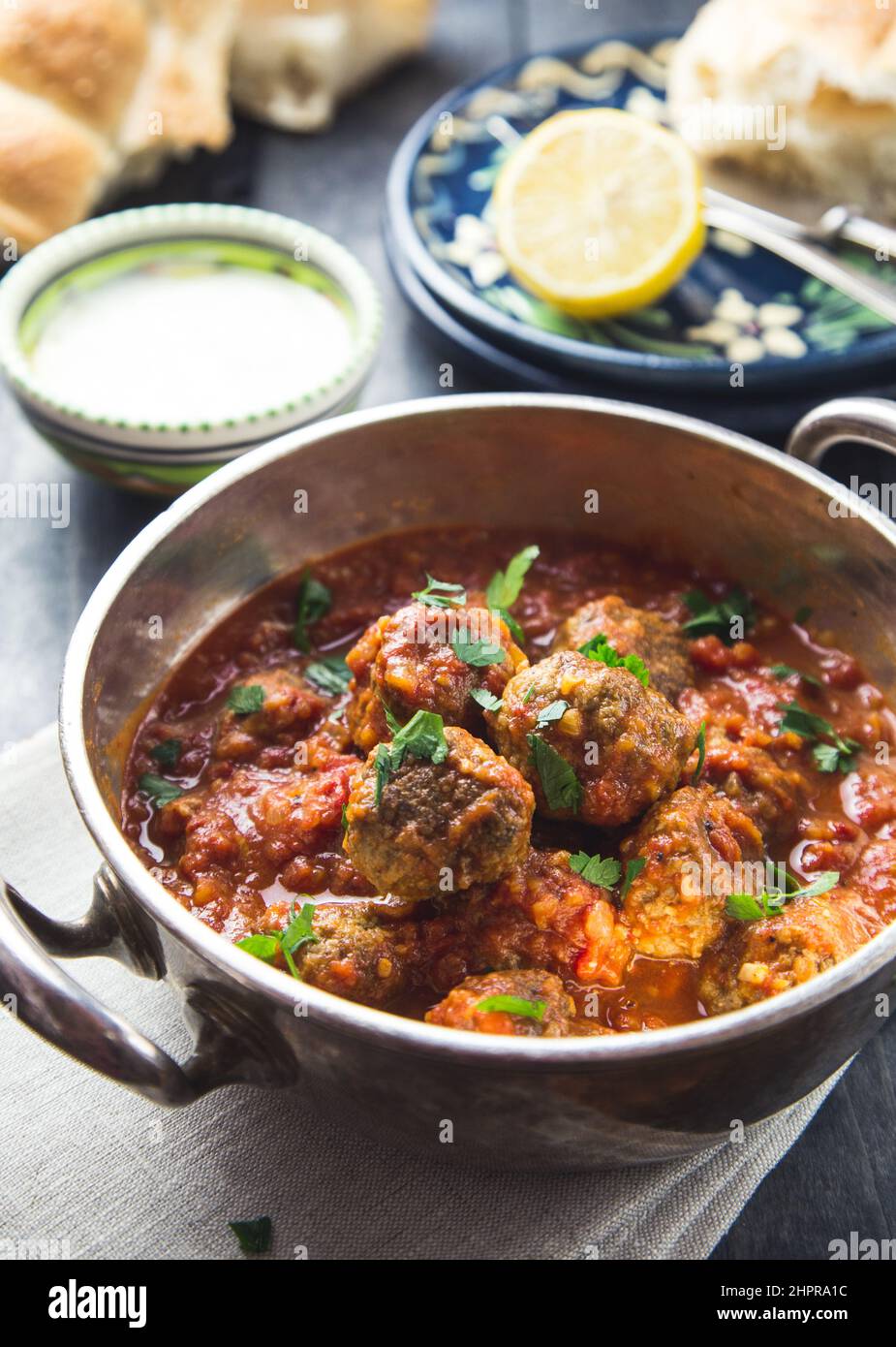 A silver bowl full of meatballs in tomato sauce in a dark rustic