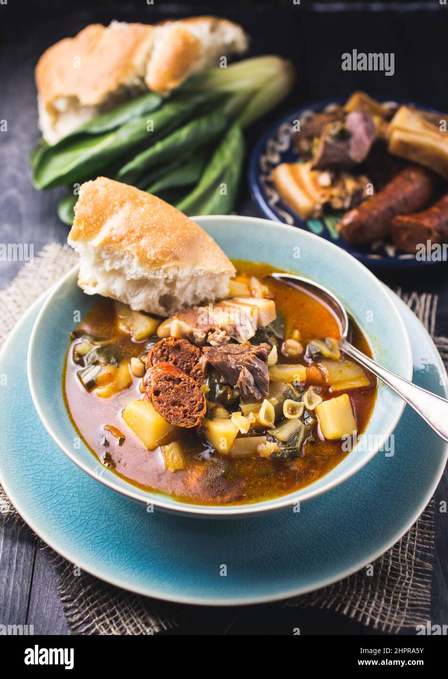 A blue bowl of Spanish chard stew with beans, potatoes, pork belly and ...