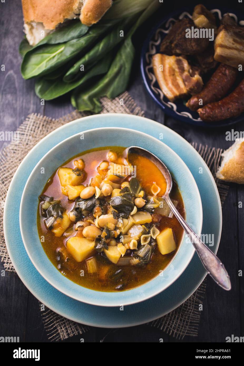 A blue bowl of Spanish chard stew with beans, potatoes, pork belly and ...