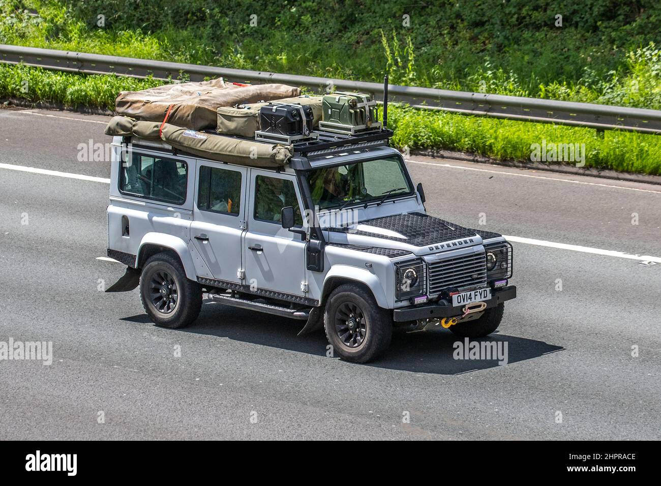 2014 white Land Rover Defender 2198cc 6-speed manual with overland expedition camping gear, spare fuel cans, winch and canvas tents. Stock Photo