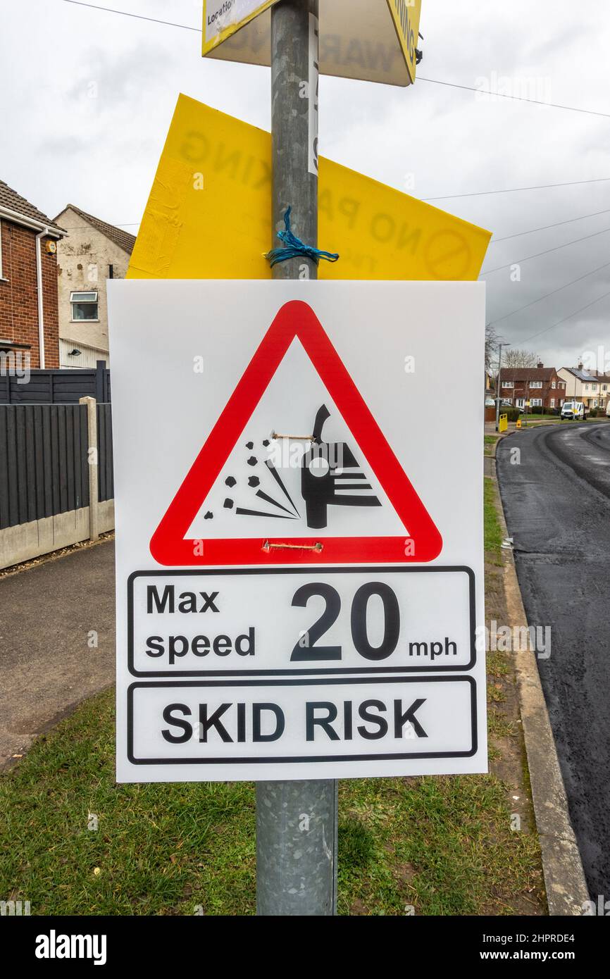 Temporary road sign attach to a lamppost warning of a skid risk and