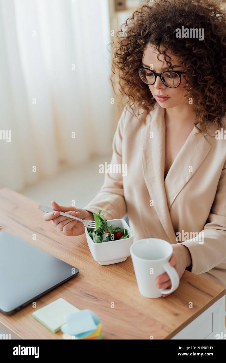 Woman eat healthy green food in the office near notebook. Work space Stock Photo