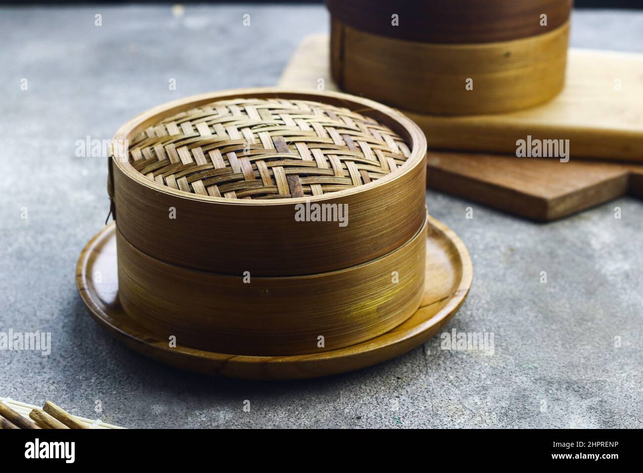 Bamboo steamer for dim sum or chinese food with wooden chopstick. Grey grainy background. selective focus. Copy space for text. Stock Photo