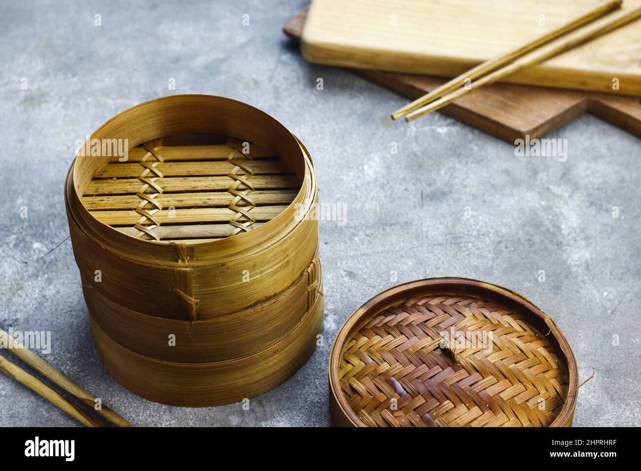 Bamboo steamer for dim sum or chinese food with wooden chopstick. Grey grainy background. selective focus. Copy space for text. Stock Photo