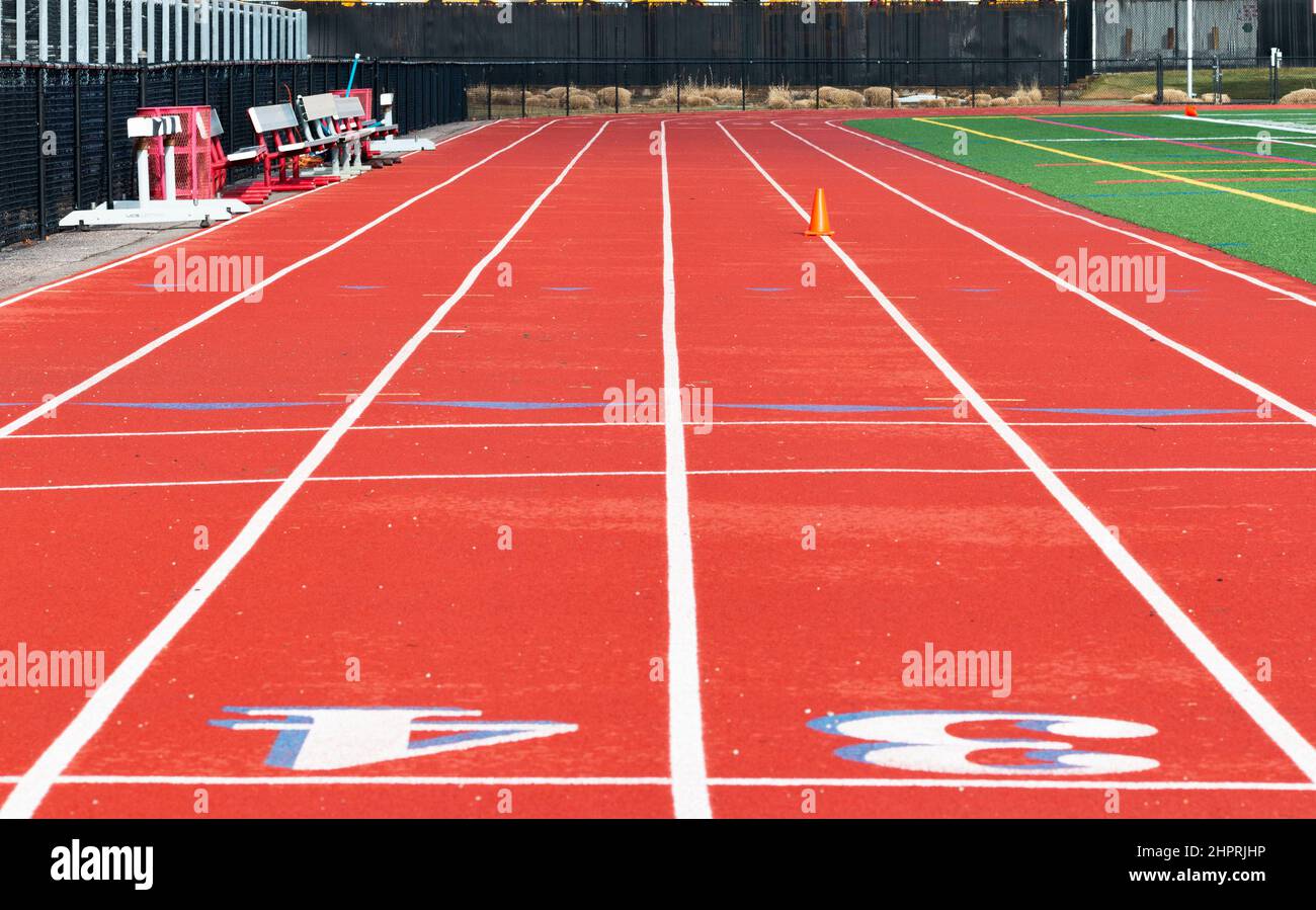 Looking doewn a red track with blue outlines from the finish line to the 100 meter start line. Stock Photo