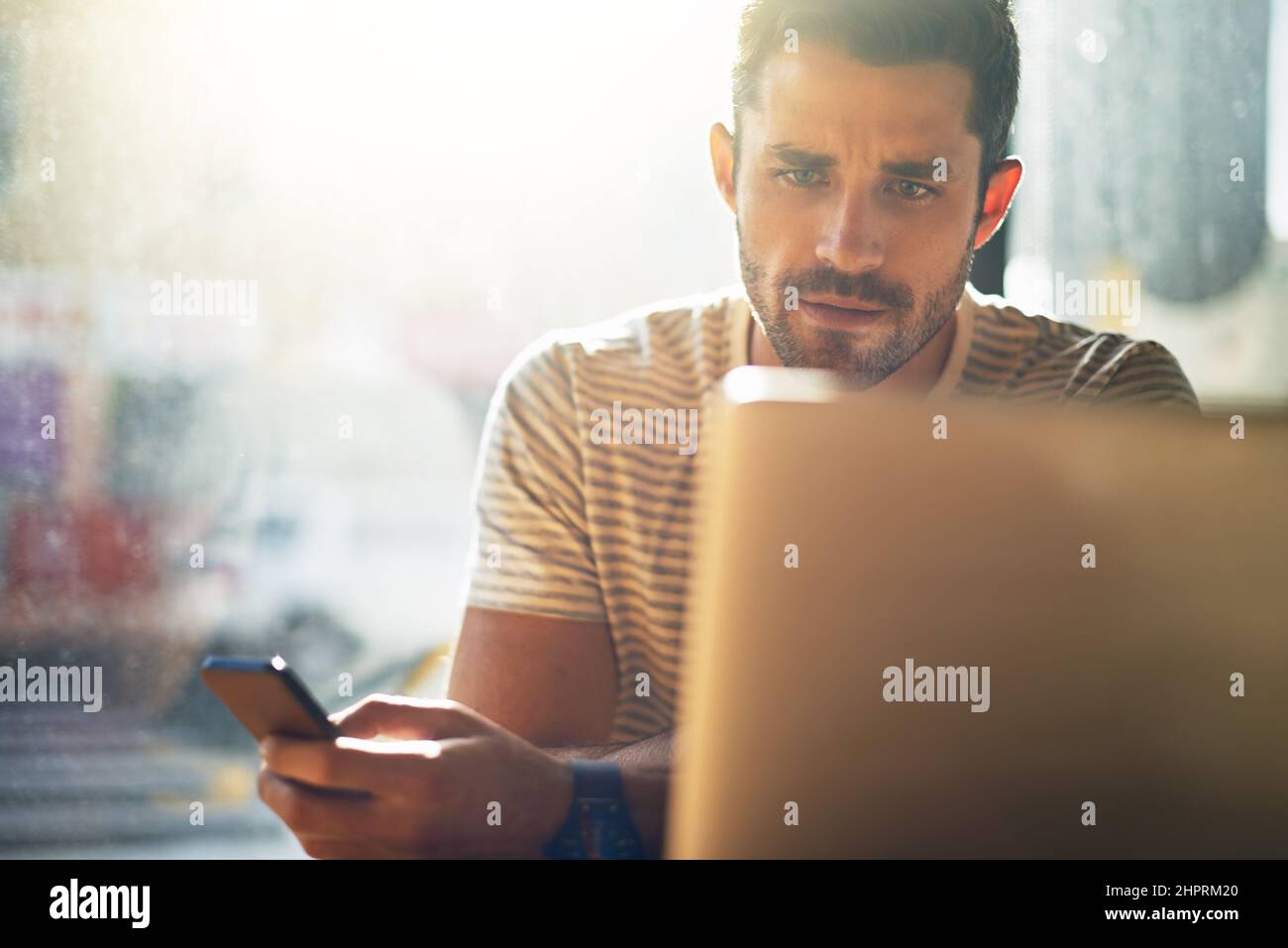 Getting some admin done. Shot of a young man using his laptop in a coffee shop. Stock Photo