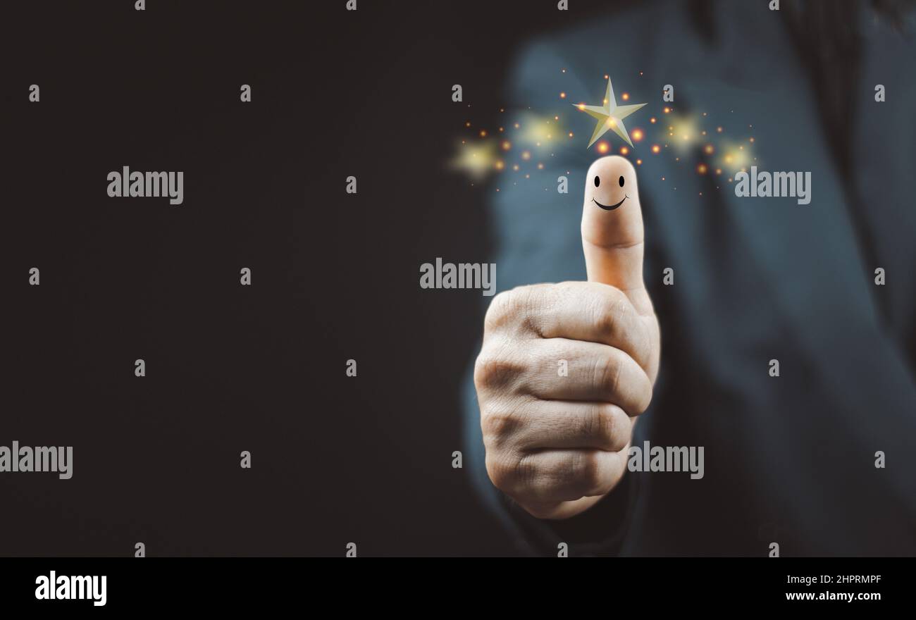 Customer satisfaction concept. Hand with thumb up Positive emotion smiley face icon and five star with copy space. Stock Photo