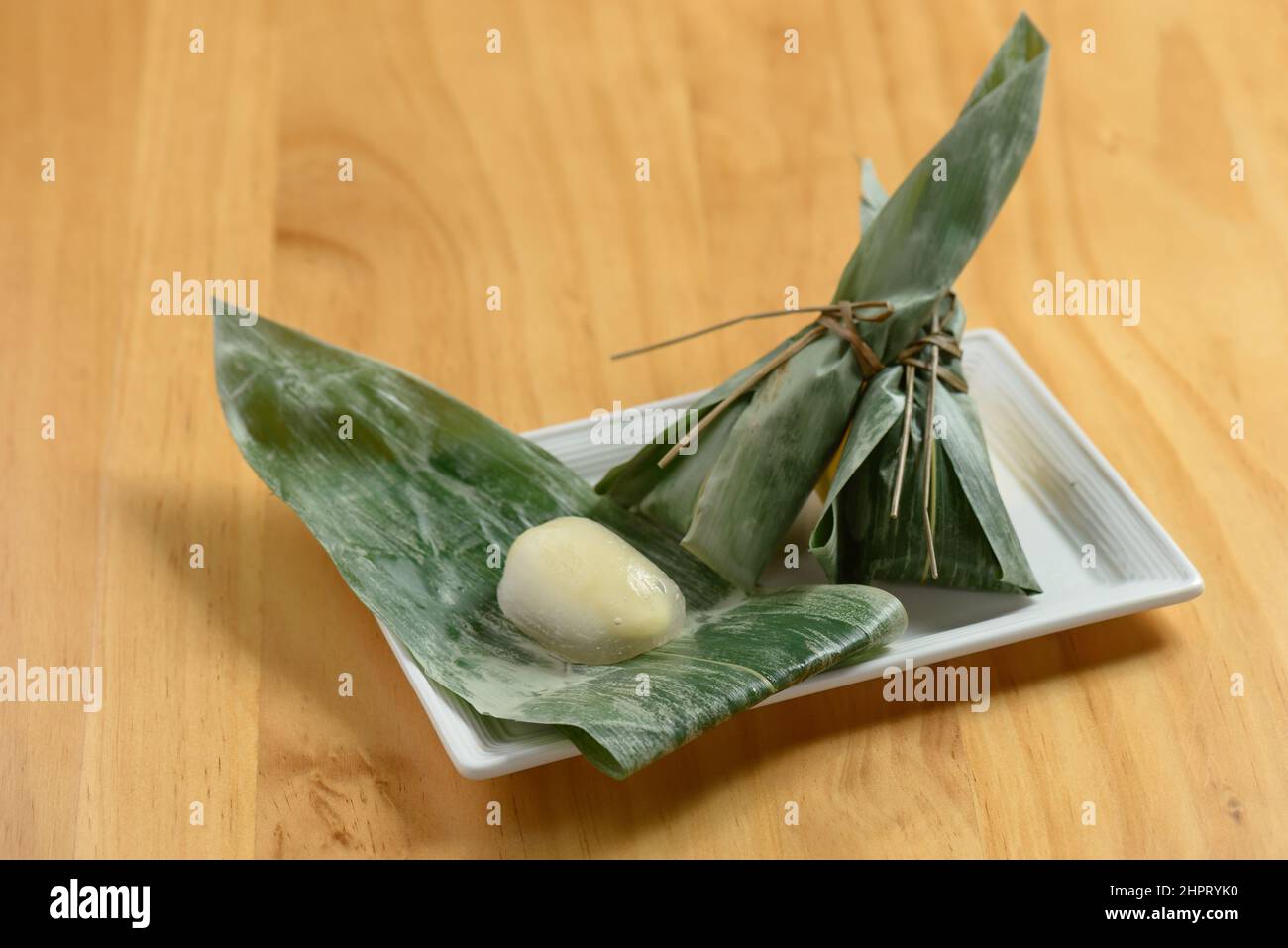 Japanese food sasa mochi rice cake wraps with banana leaf in a dish isolated on wooden background top view Stock Photo