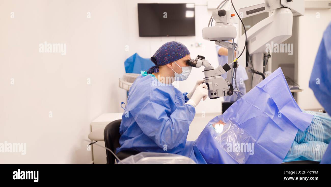 A surgeon looking through his surgical microscope during an eye surgery Stock Photo