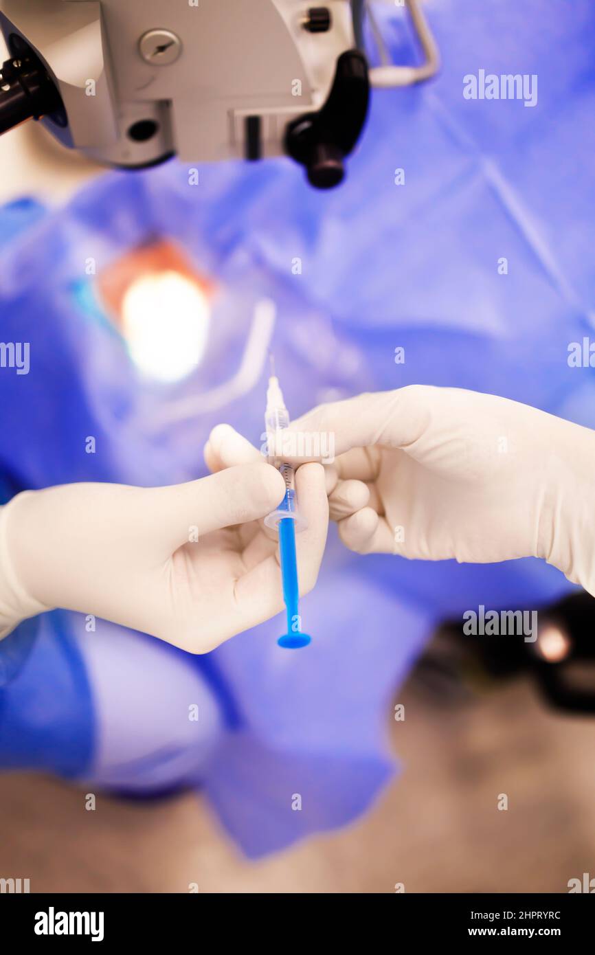 Detail of a nurse handing out a syringe to a surgeon during the operation Stock Photo