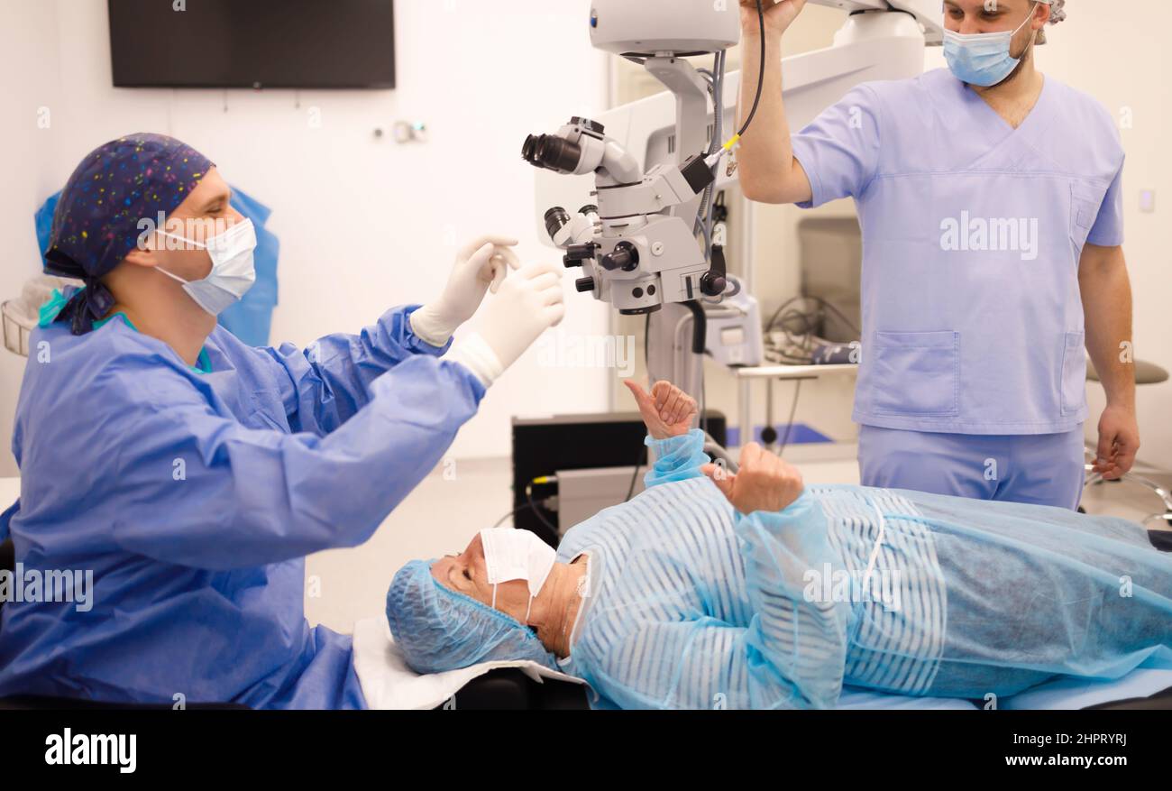Surgeon, patient and a technician with masks smiling prior to an eye surgery Stock Photo