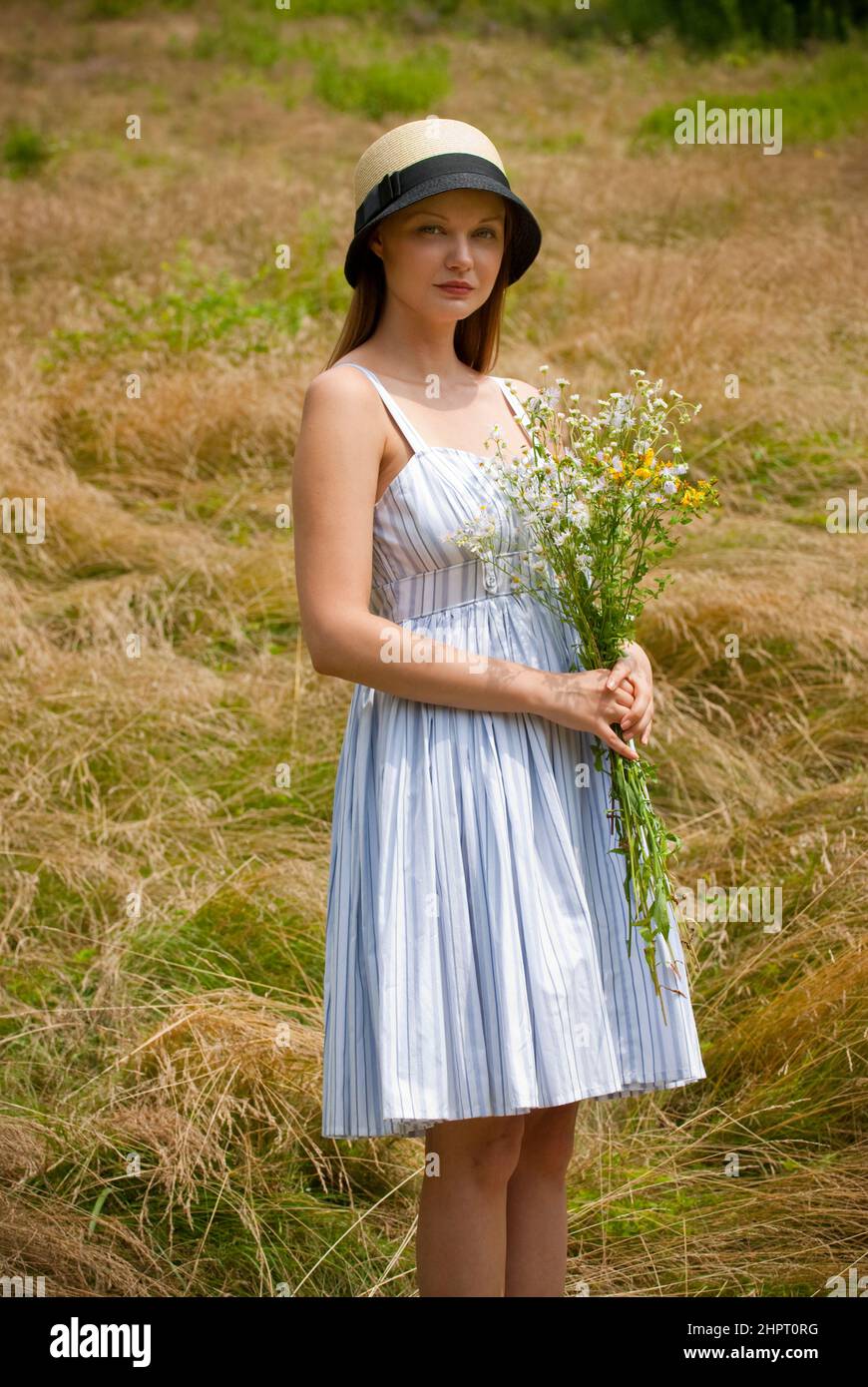 Young woman standing in a field holding a bouquet of wild flowers Stock ...