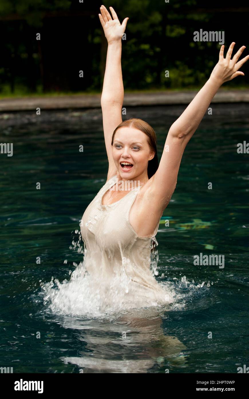 Woman in bikini splashing and smiling in pool Stock Photo