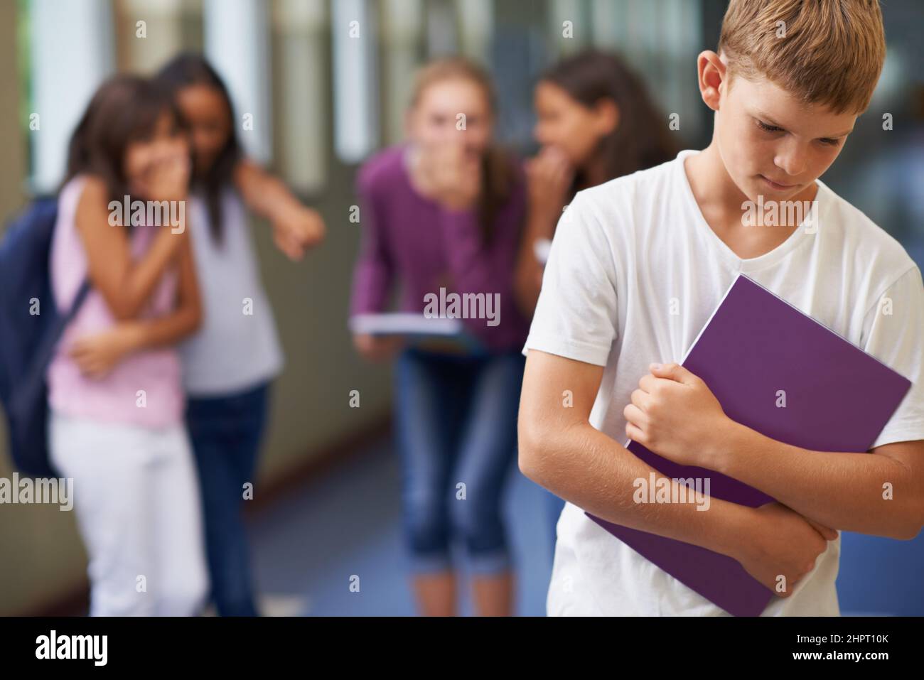 Being made to feel like an outcast. A young boy being bullied at school. Stock Photo