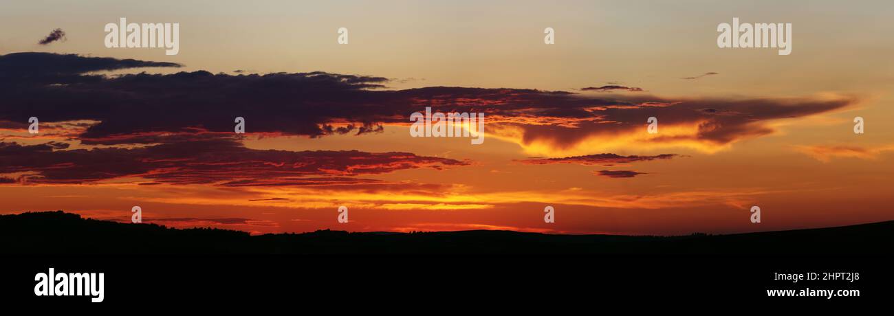 Sunset panorama. Dramatically fiery sky with clouds. Beautiful landscape. Stock Photo